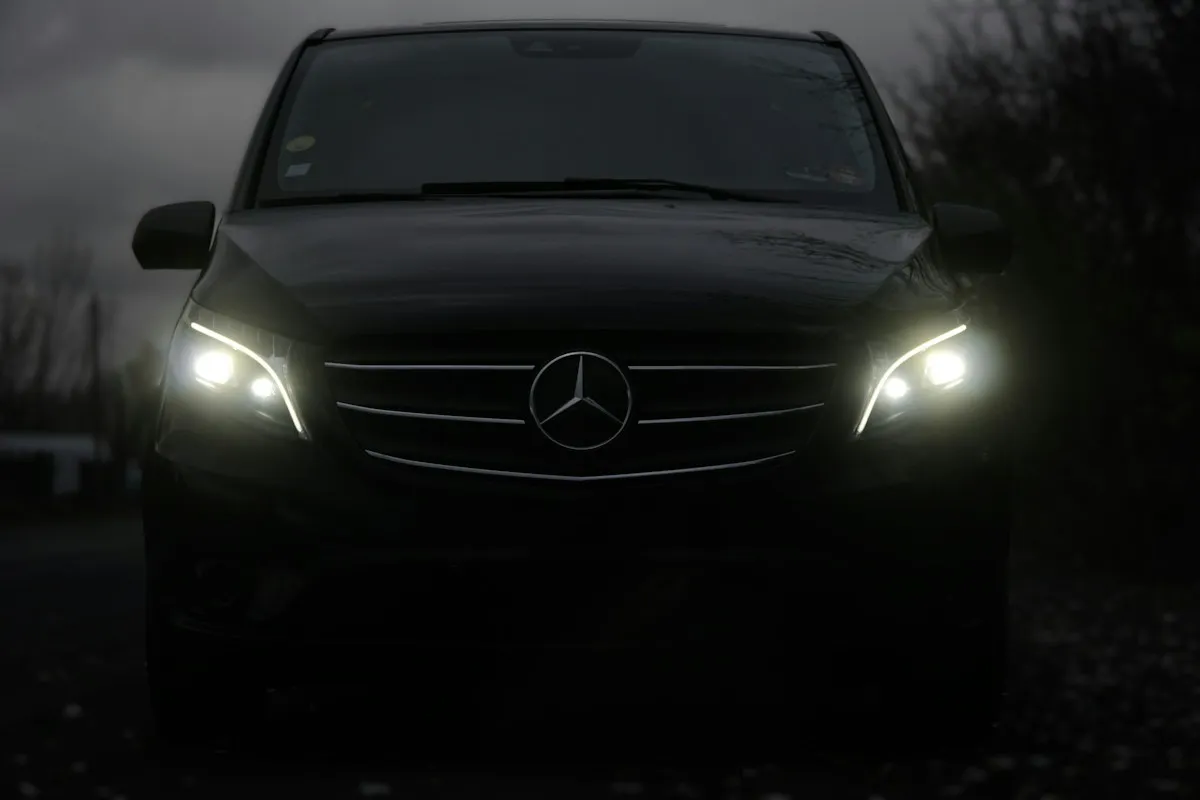 Dark Mercedes van for private transfers with headlights on